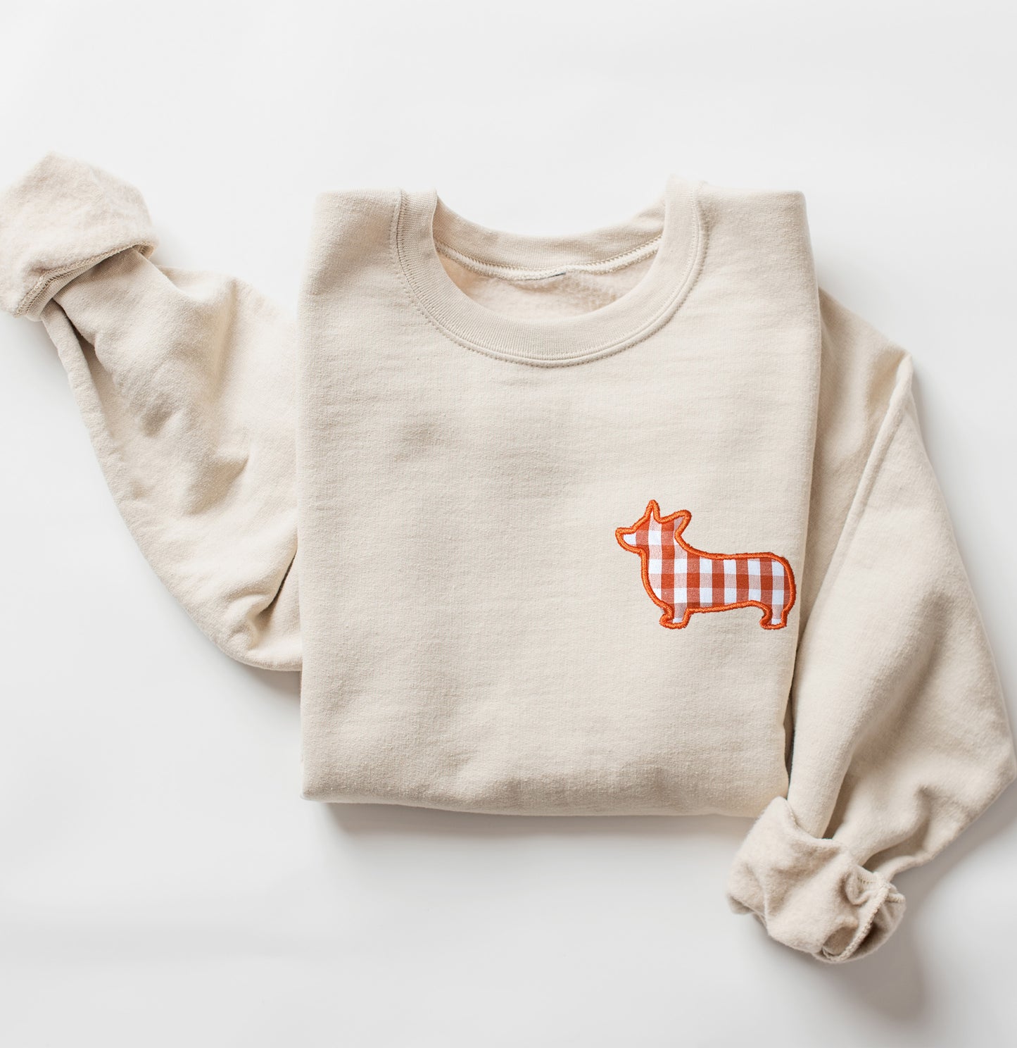 Beige sweatshirt with a orange and white corgi dog graphic on a white background